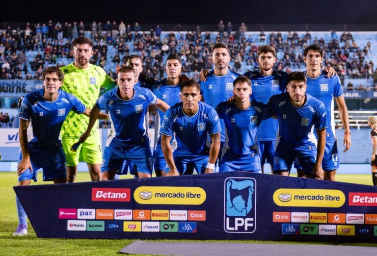 Escudo de Estudiantes de Río Cuarto en primer plano, con fondo relacionado al fútbol profesional.