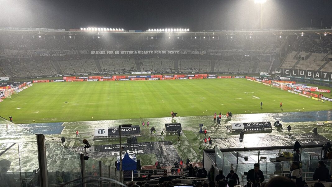 Personal del estadio Mario Alberto Kempes trabaja en el campo de juego tras las lluvias en Córdoba.