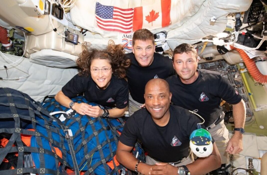 Ilustración conceptual de la nave Orion de la misión Artemis II orbitando la Luna, con la Tierra al fondo.